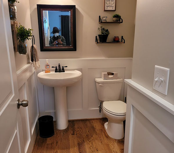 A bathroom with a toilet, sink, and mirror.