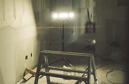 A room with a ladder and a light illuminating the ladder.