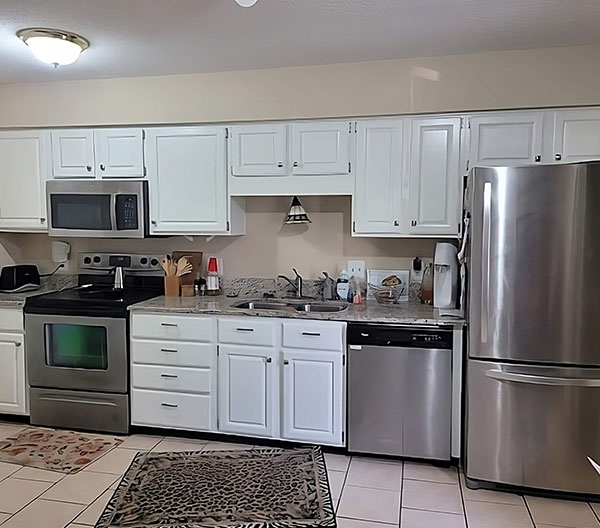 A modern kitchen with stainless steel appliances and sleek tile flooring.